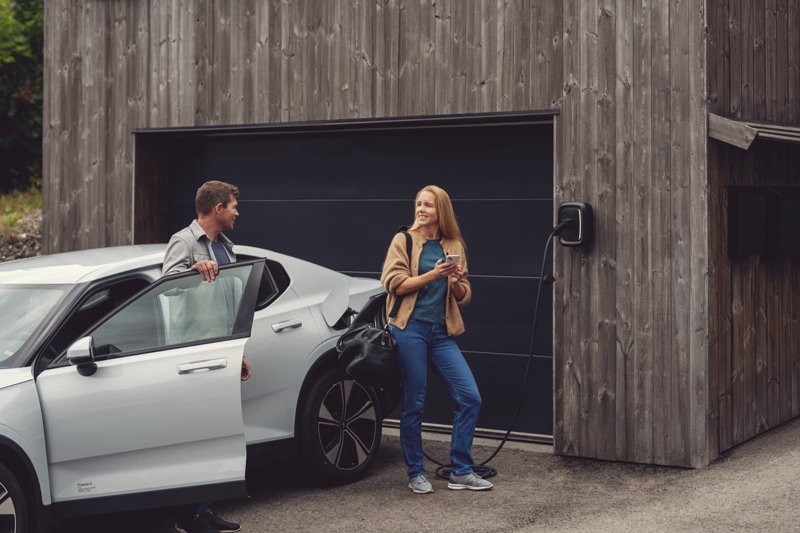 Par med elbil og hjemmelader montert på veggen